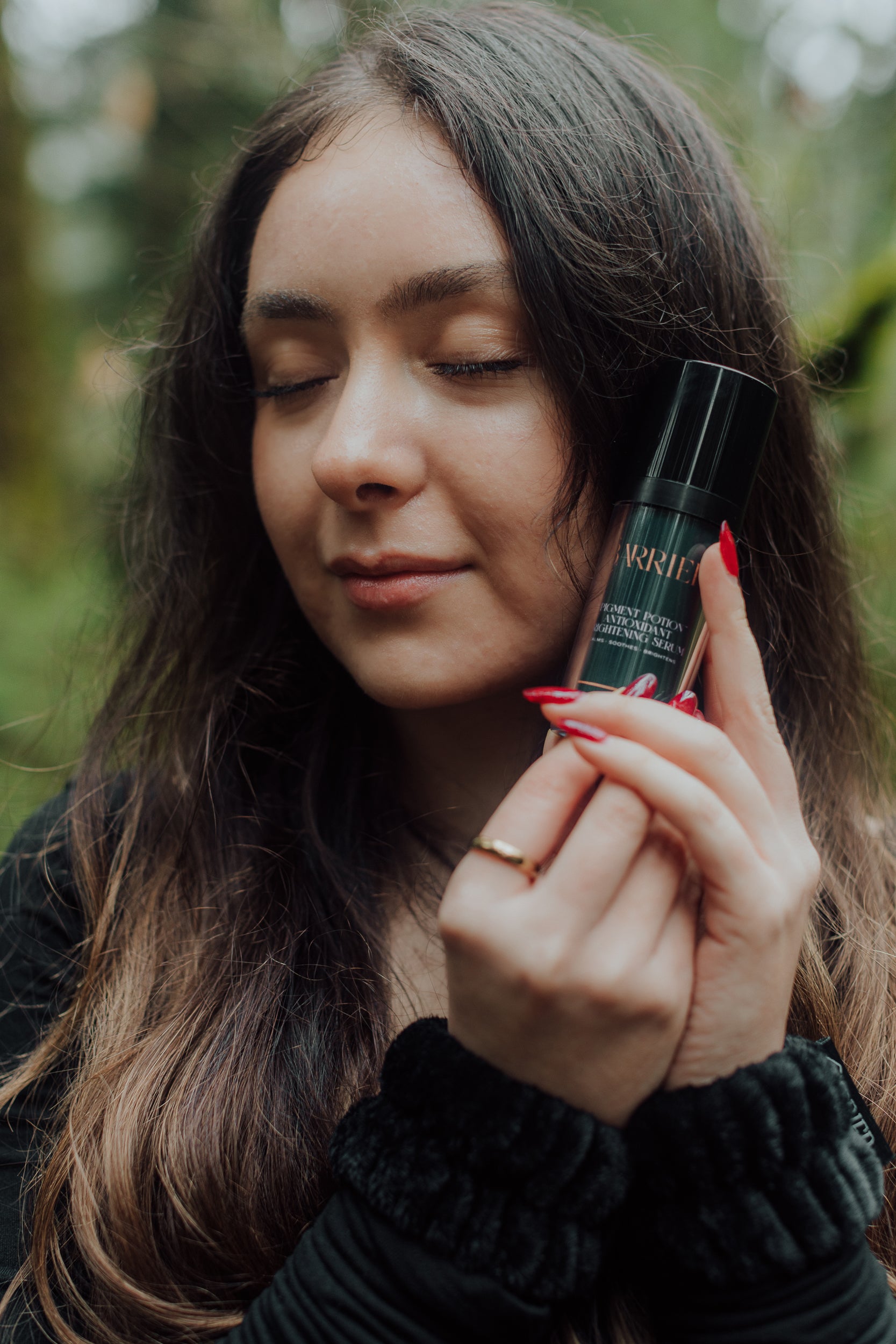 Woman holding bottle of green Barrier Plus Pigment Potion