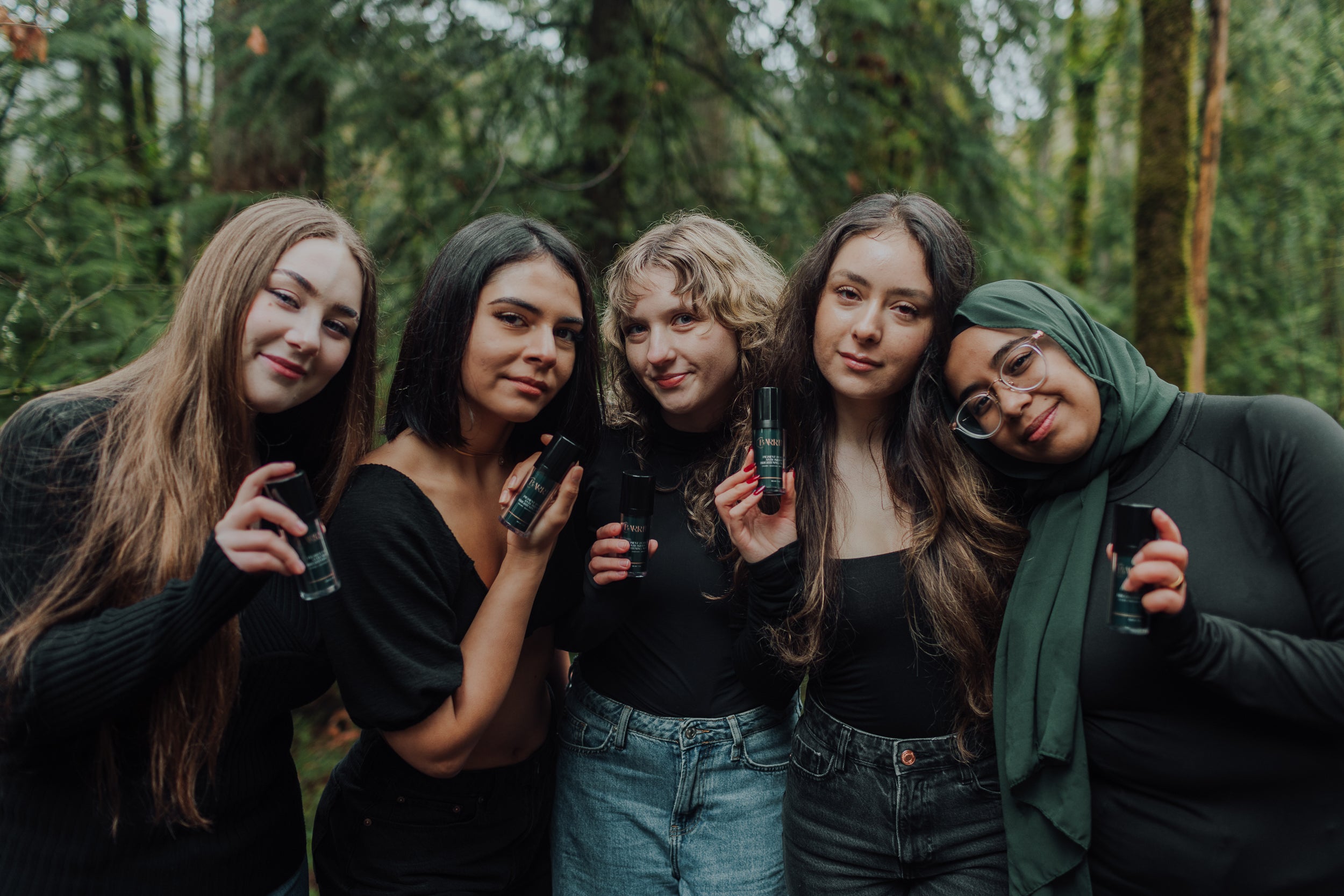 Group of women in the woods holding black and green skincare bottle of Barrier Plus Pigment Potion