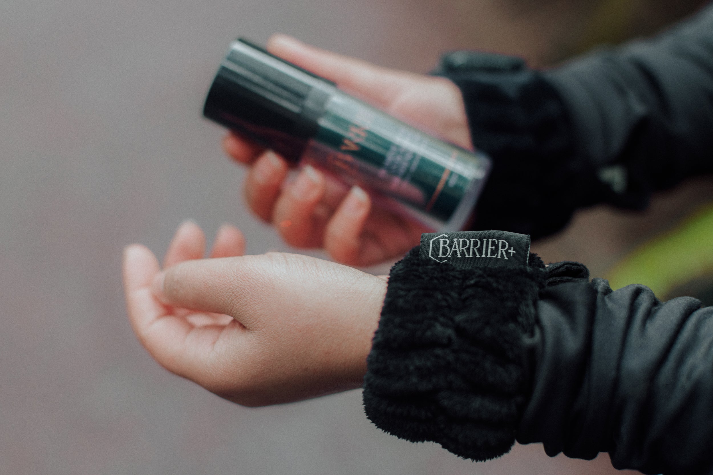 Black wrist band with name Barrier Plus on it and a bottle of Barrier Plus Skincare Serum